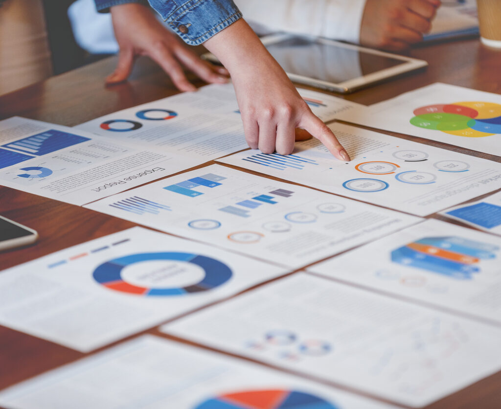 Colleagues compare data displayed on a conference table.