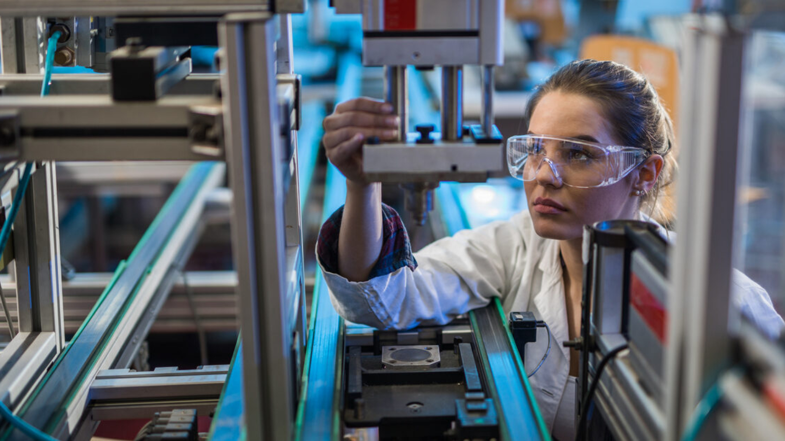 A quality control engineer examines a. machine part on a production line.