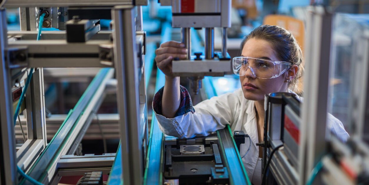 A quality control engineer examines a. machine part on a production line.